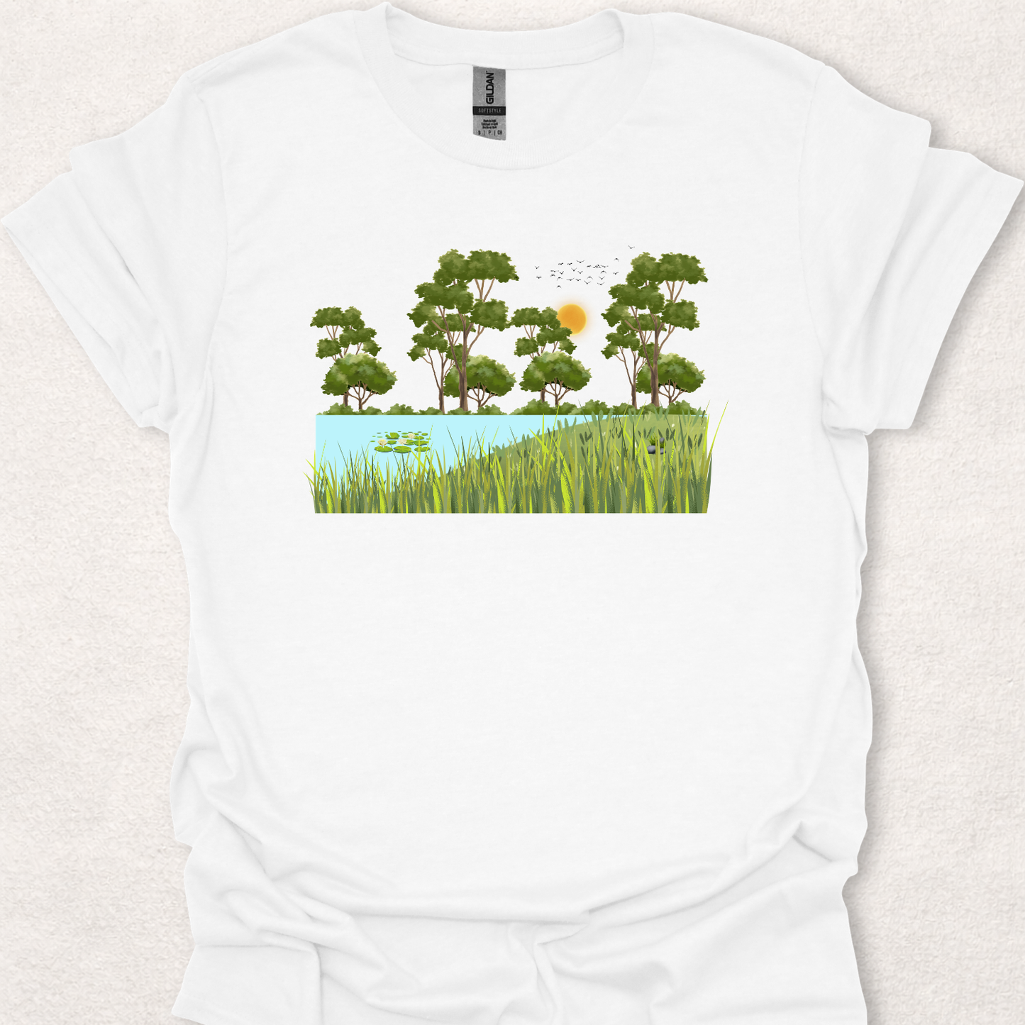 Nature-inspired landscape t-shirt featuring a peaceful pond, trees, birds, and the phrase "Peace Grows Here".