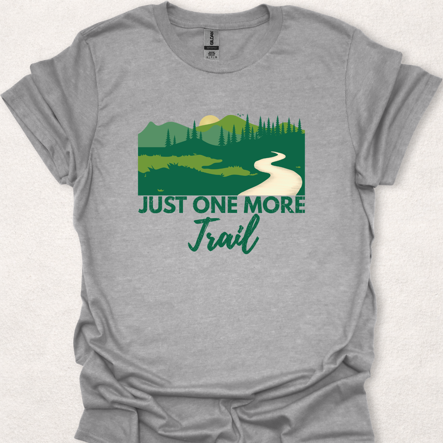 Sport grey unisex t-shirt featuring the "Just One More Trail" hiking design with a forest trail illustration inspired by outdoor adventures and nature exploration.
