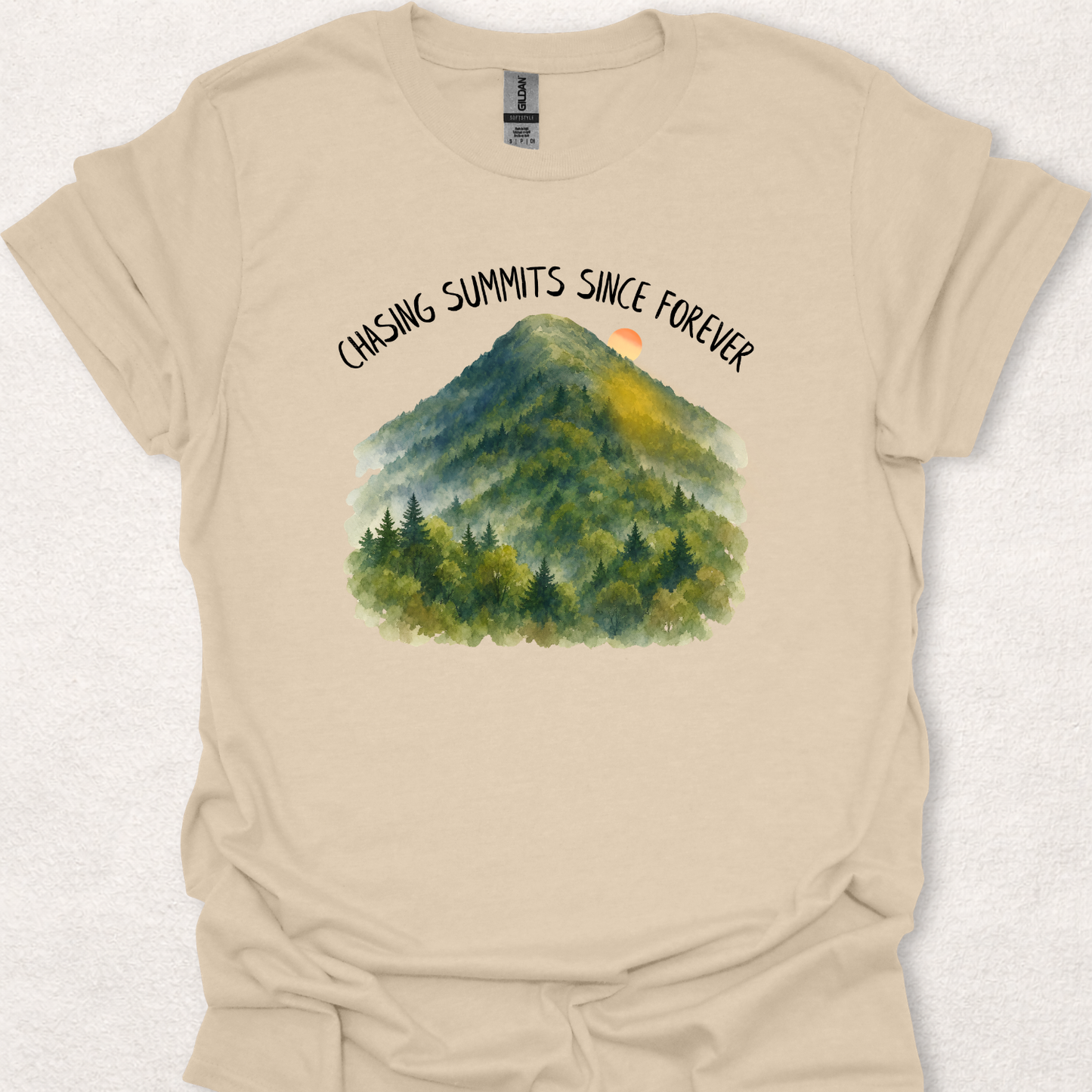 Sand t-shirt featuring the Chasing Summits Since Forever mountain graphic with a watercolor forest landscape and sunrise.
